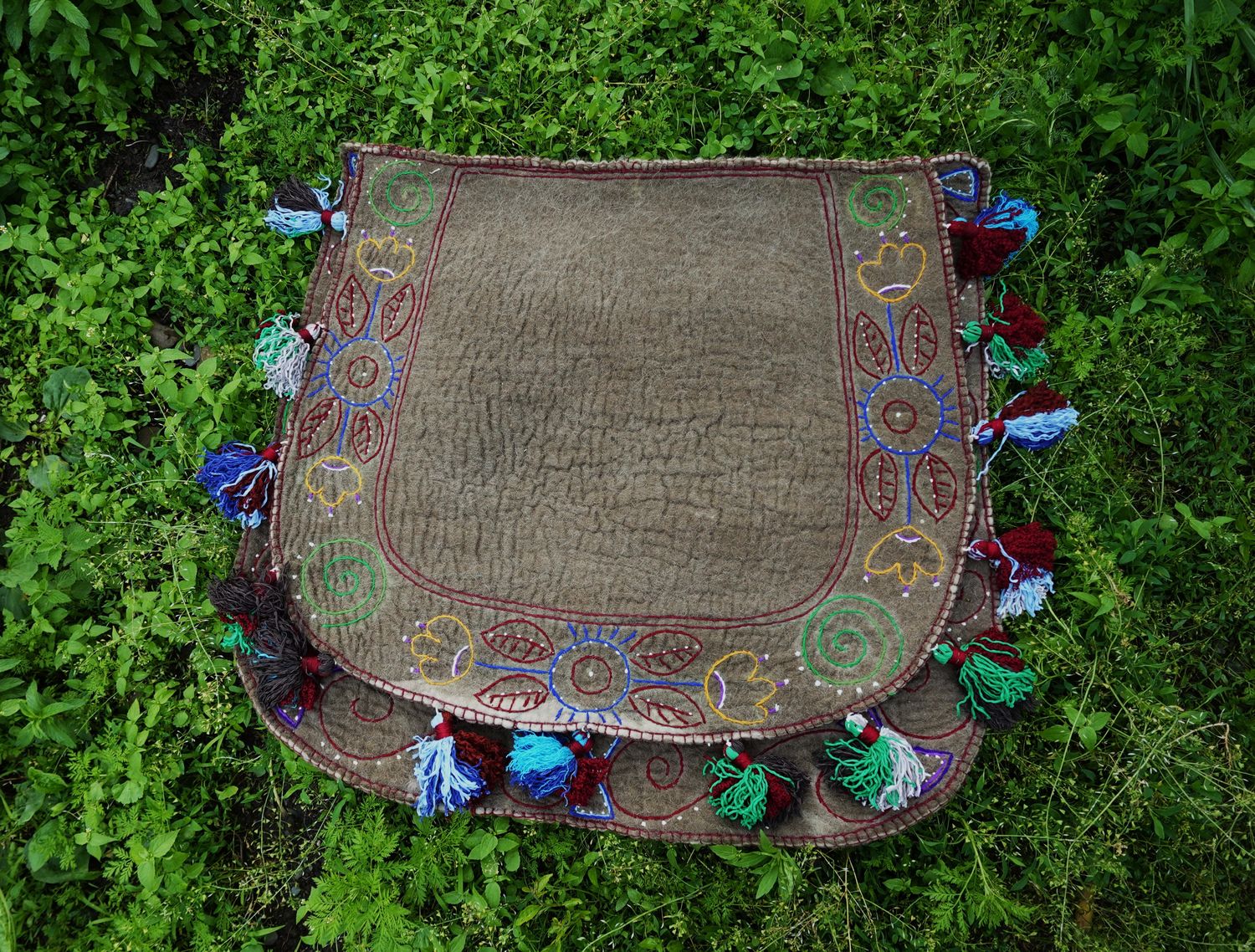 Felt Shabrak with embroidered tassel border laid flat on grass