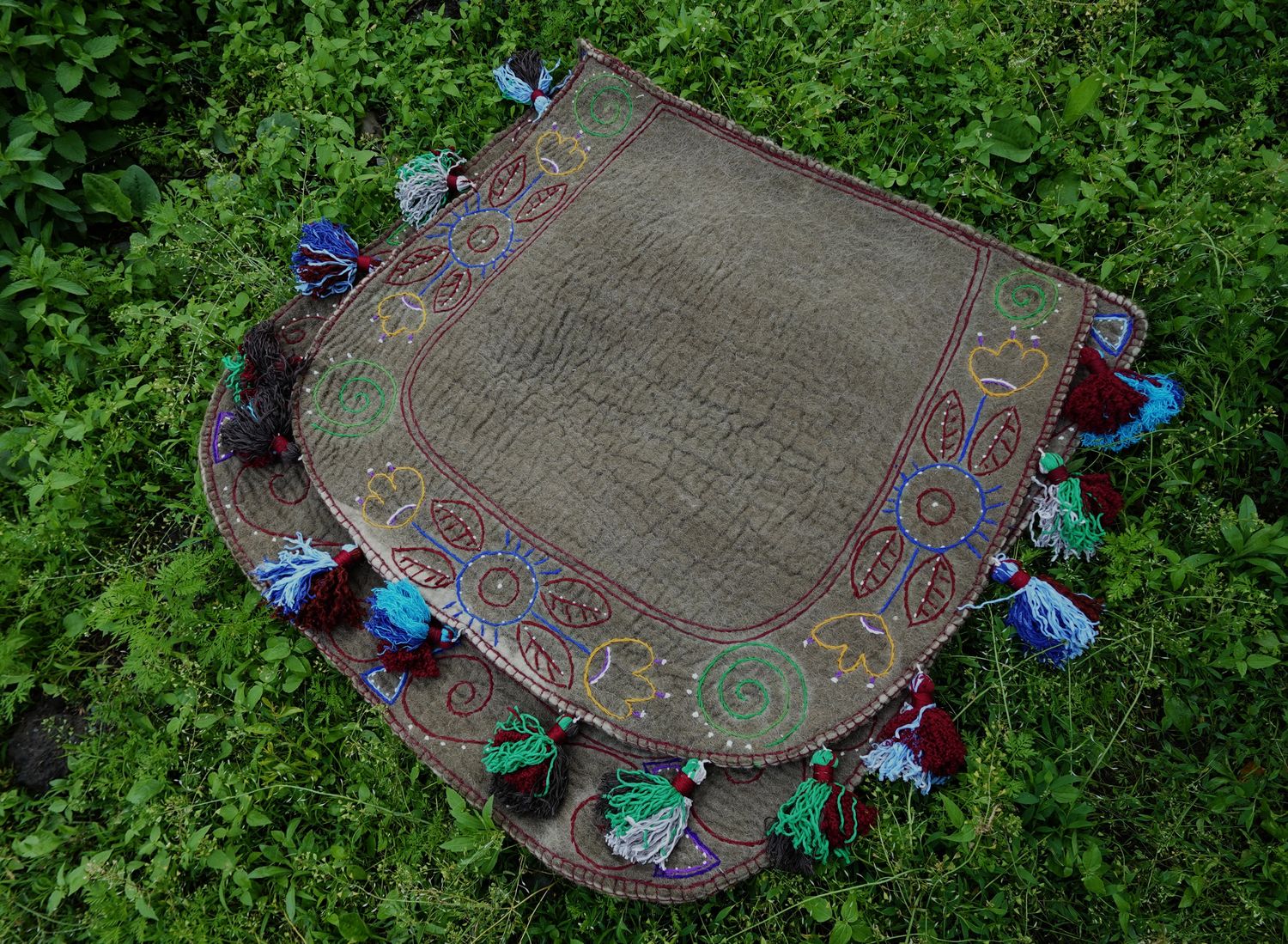 Grey-brown felt Shabrak with multicoloured embroidery and tassels on grass
