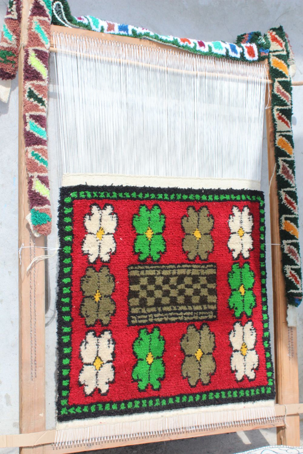 A red and white flower pattern taking shape on the loom