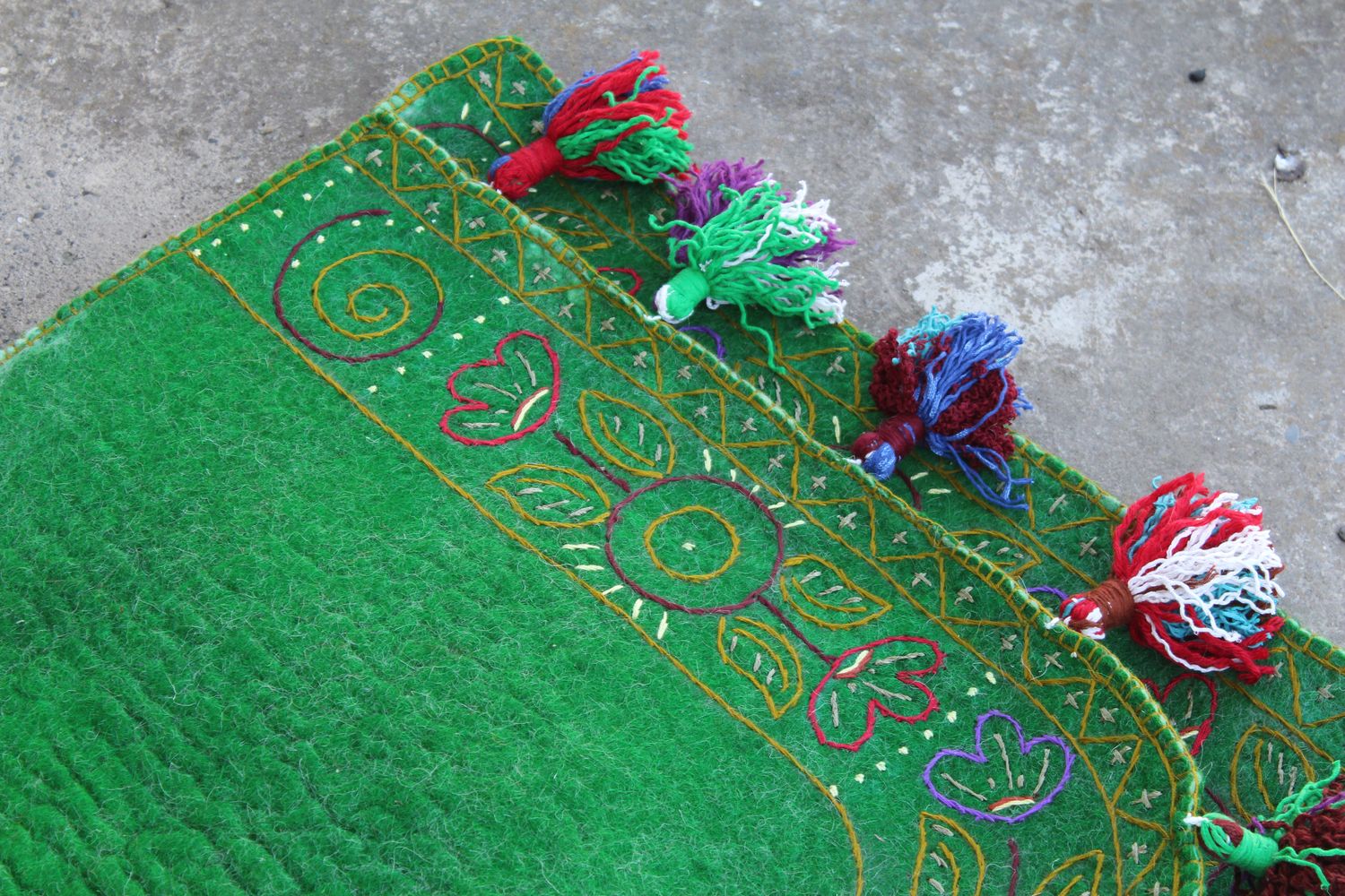 Detail of green felt with embroidery and tassels