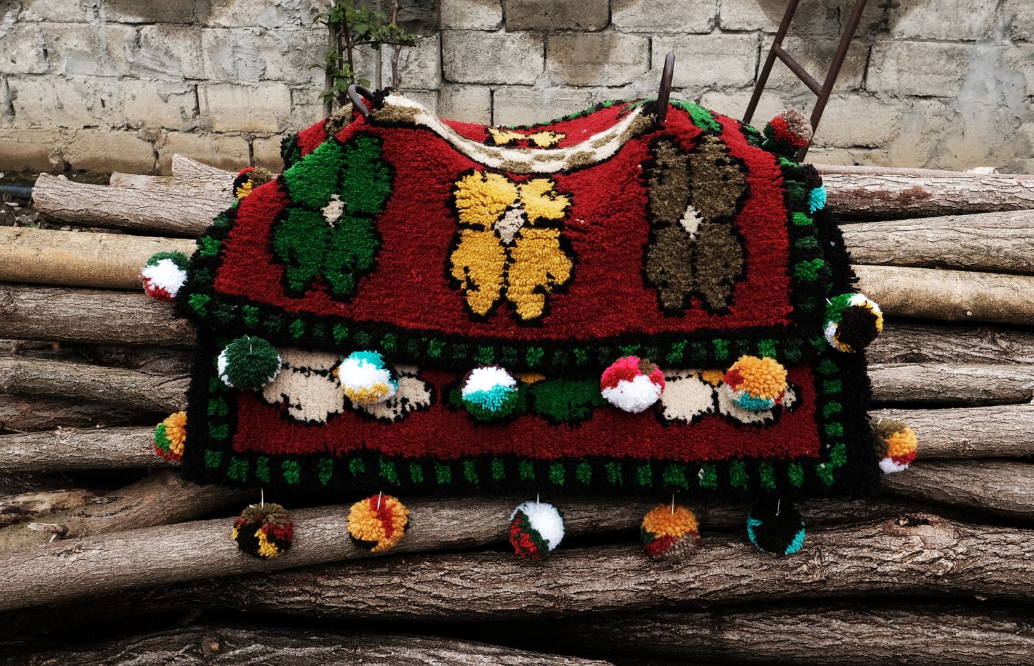 Hand-woven red Shabrak with green and yellow flowers on weathered logs