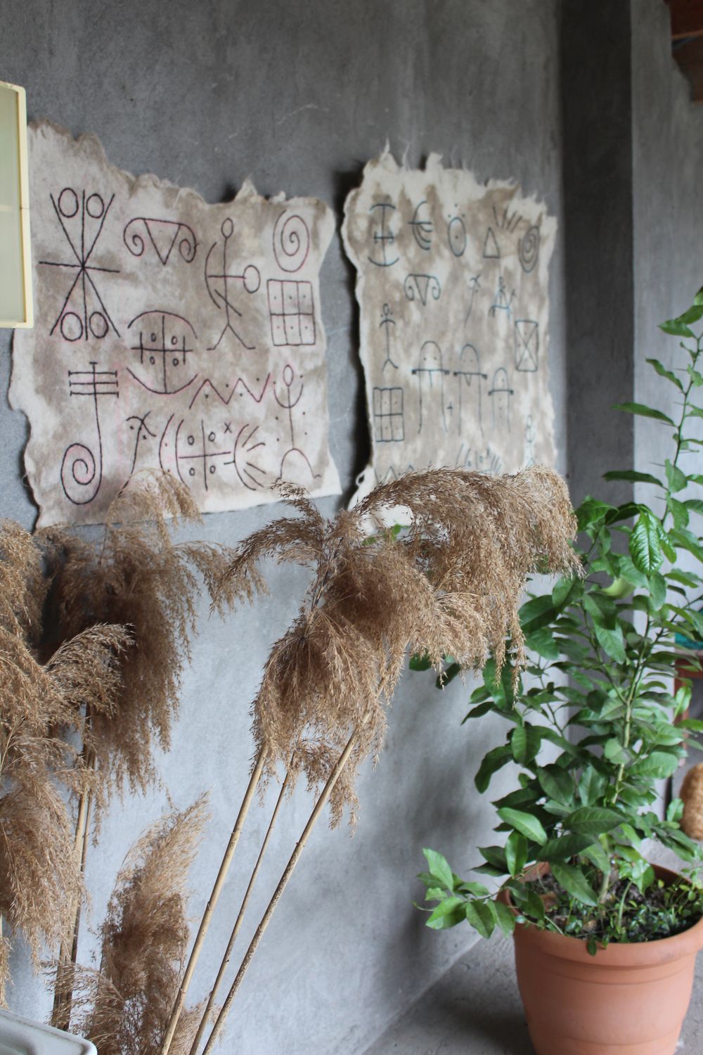 Two felt pictogram panels side by side with dried grasses and plants