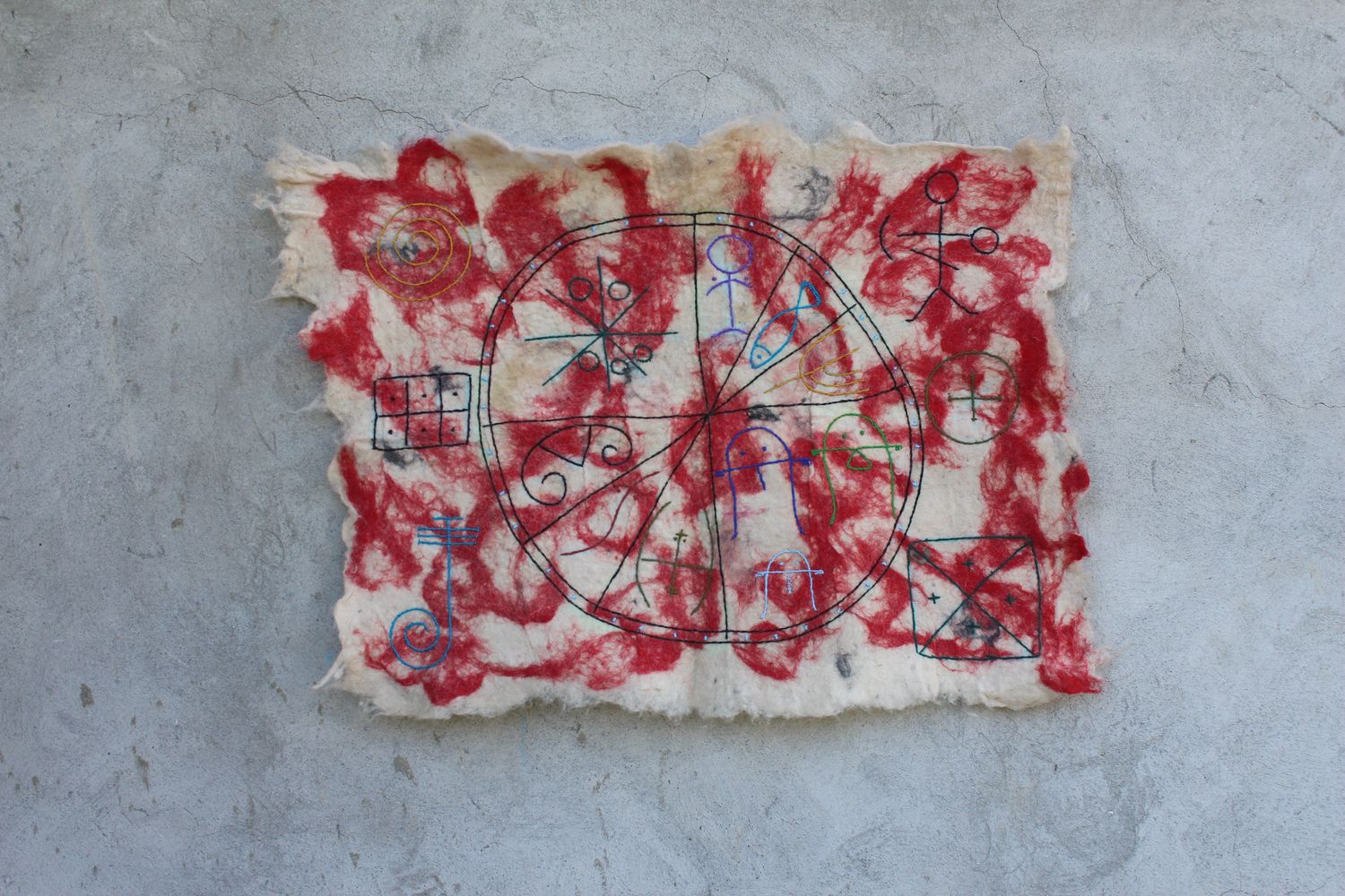 Natural felt panel with red wool symbols